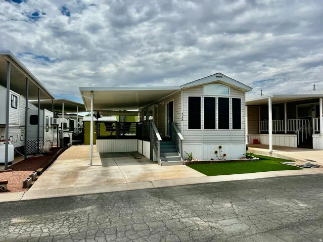 White vinyl siding exterior with an attached carport, covered patio, and a dedicated parking pad