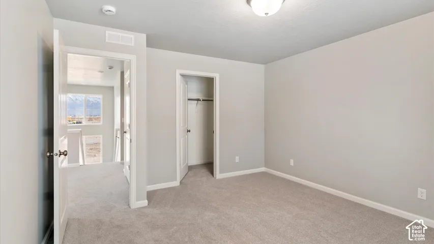 Carpeted interior space with light gray wall paint, a flush-mount ceiling light fixture, and a built-in closet