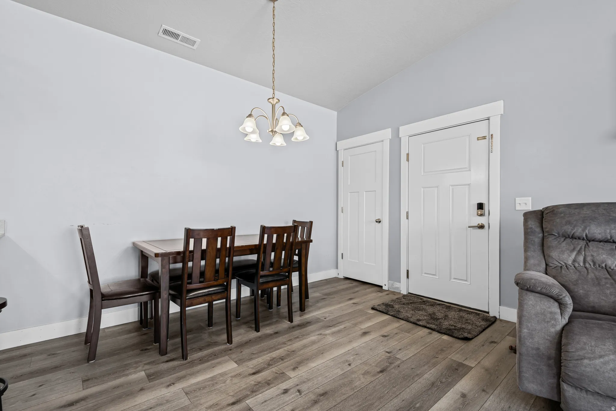 Wood-finish flooring, vaulted ceiling, and classic overhead lighting