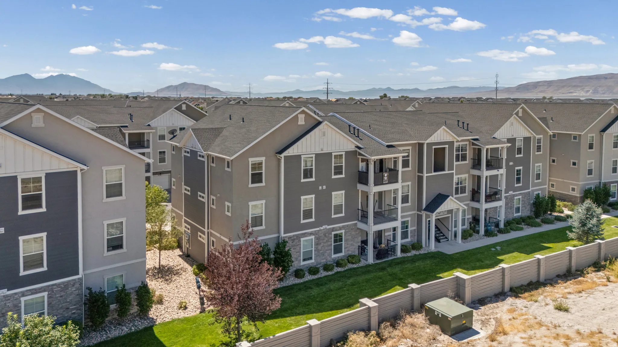 Multi-story building featuring balconies, dark gray siding, light gray siding, and stone accents