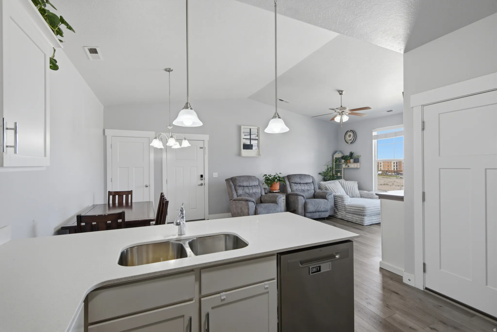 Kitchen island with a double stainless steel sink, light-toned countertops, and integrated dishwasher
