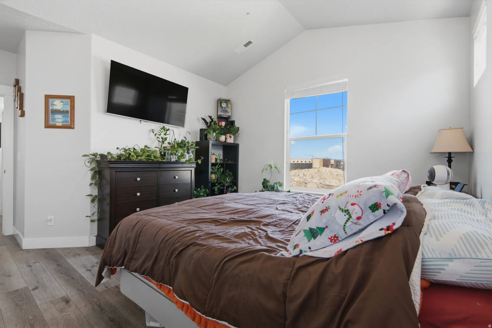 Vaulted ceiling, wood-finish flooring, and a large window providing ample natural light