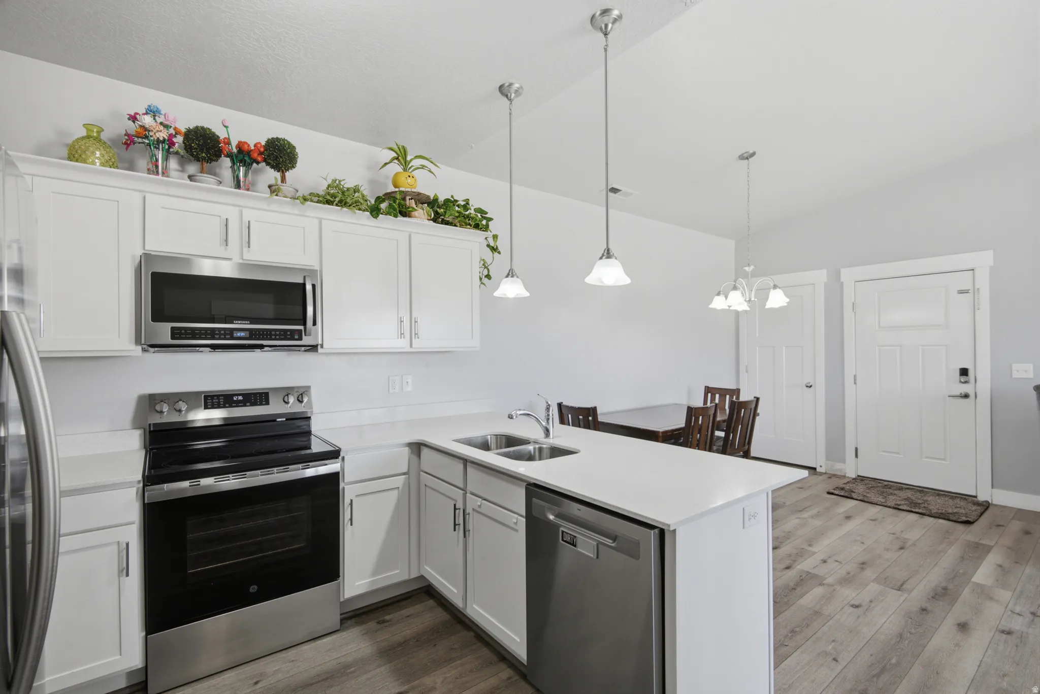 Open-concept kitchen with white cabinetry and stainless steel appliances