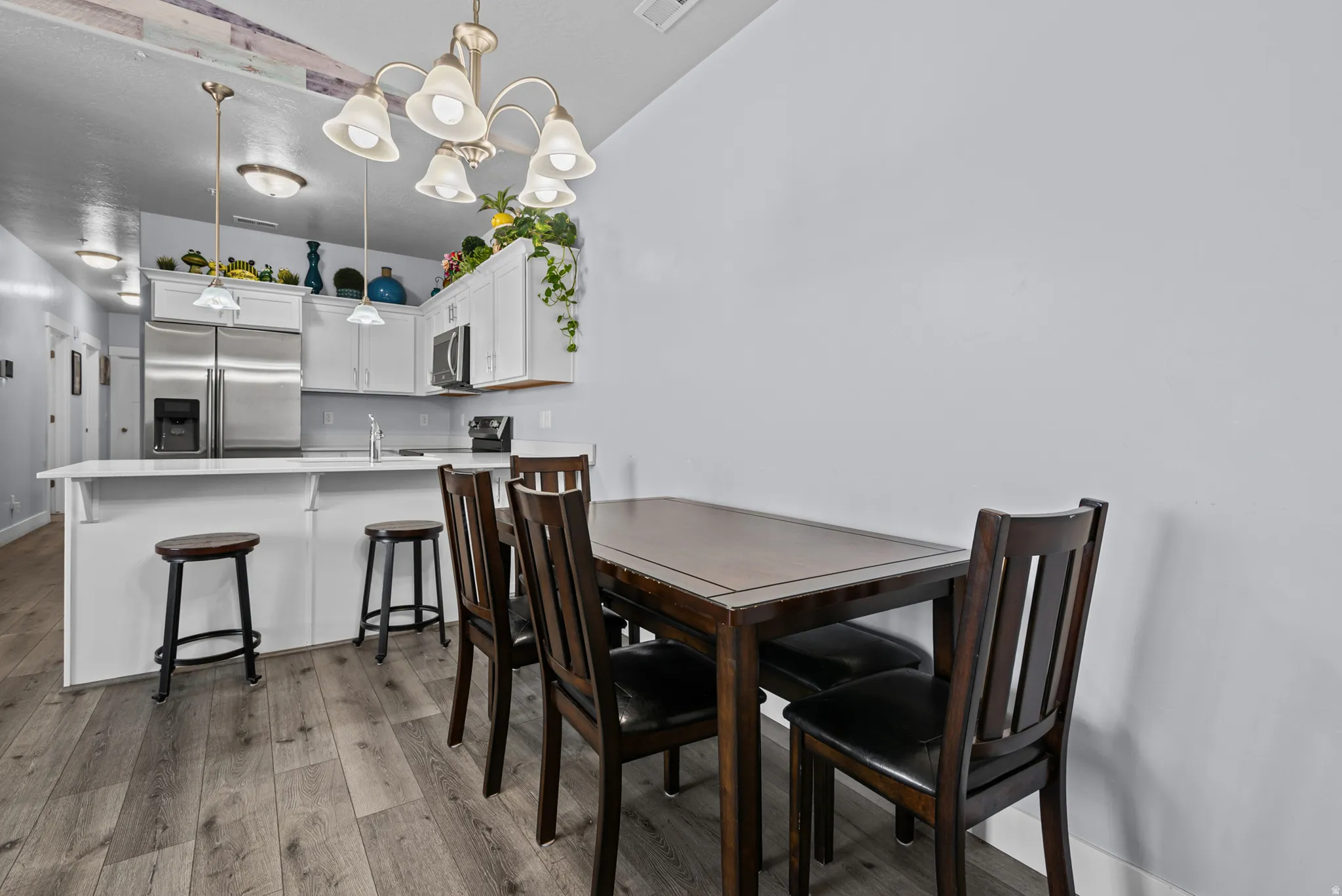 Open-concept kitchen with wood-finish flooring, white cabinetry, and stainless steel appliances