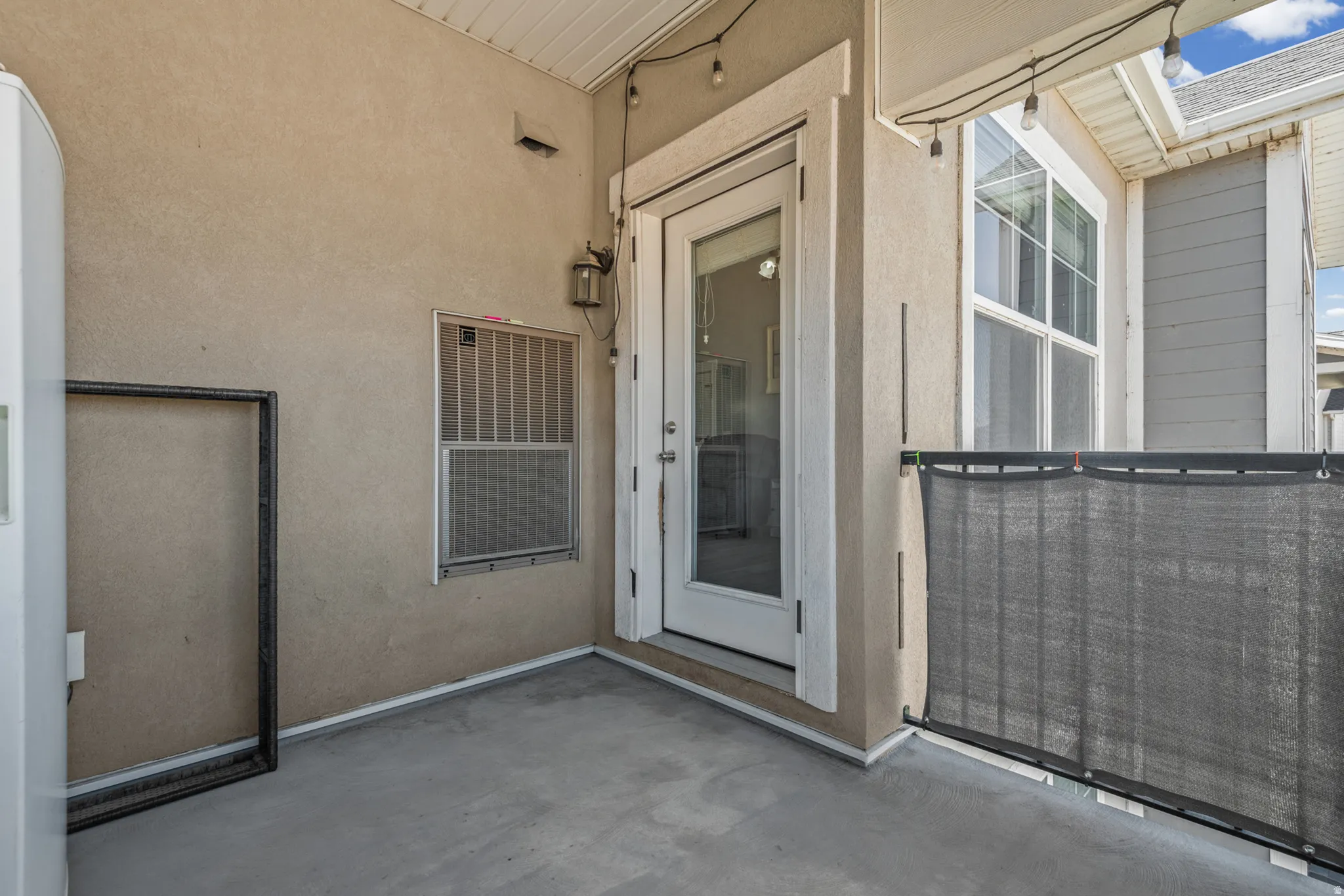 Outdoor patio featuring a painted concrete floor, stucco exterior, and an exterior light fixture