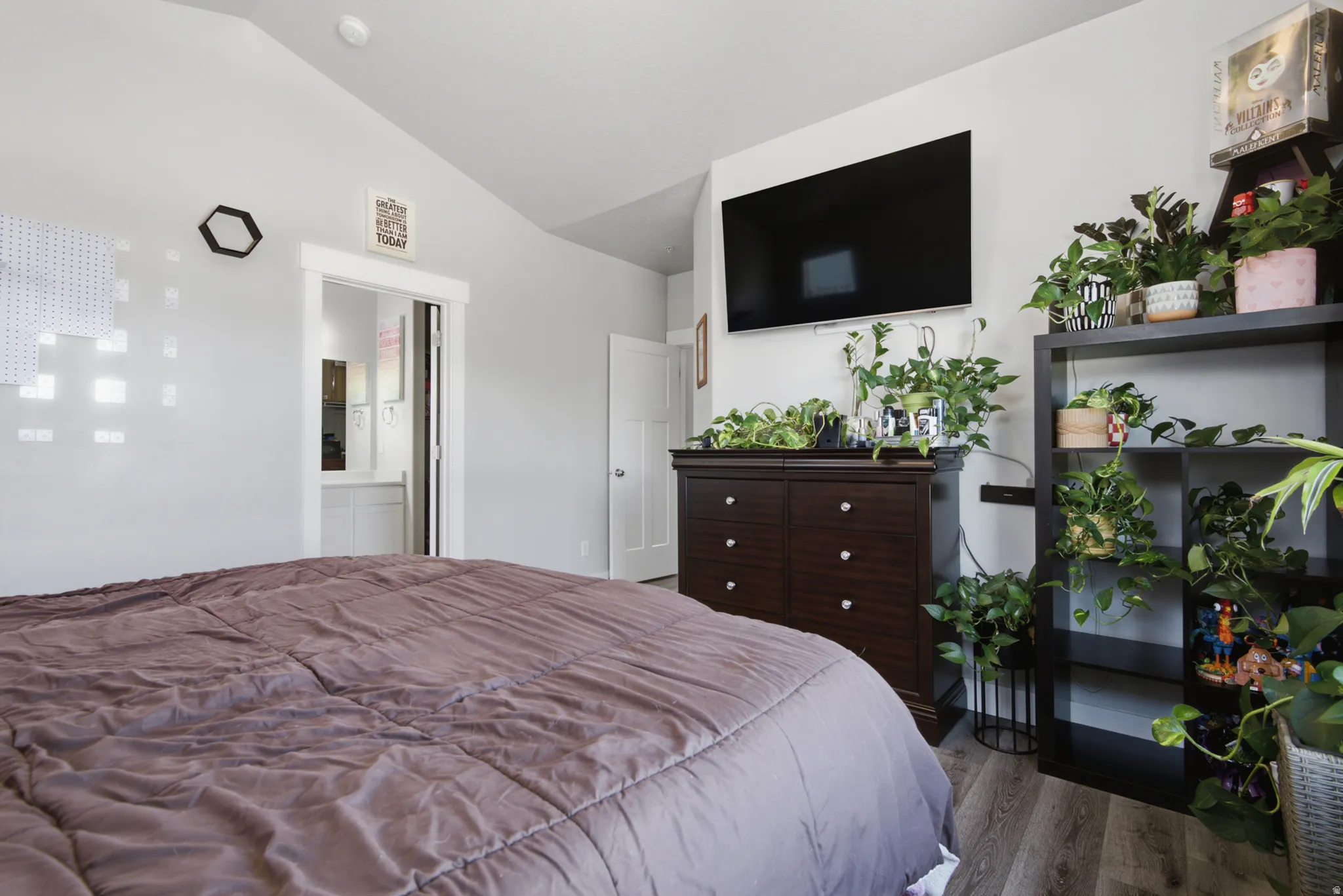 Vaulted ceiling, wood-finish flooring, white trim, and a white interior door
