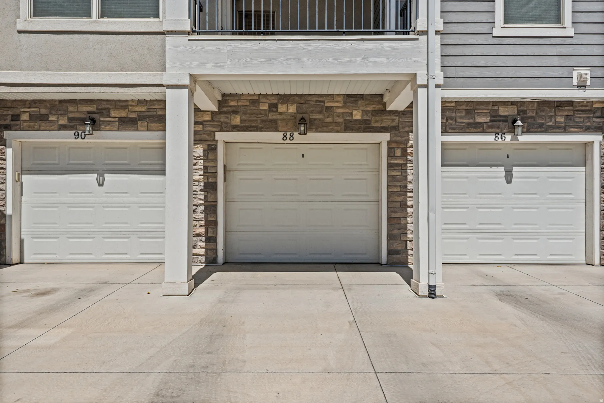 Concrete driveway with three individual garage doors, each featuring panel detailing