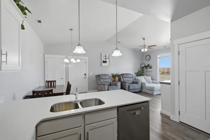 Kitchen island with a double stainless steel sink, light-toned countertops, and integrated dishwasher