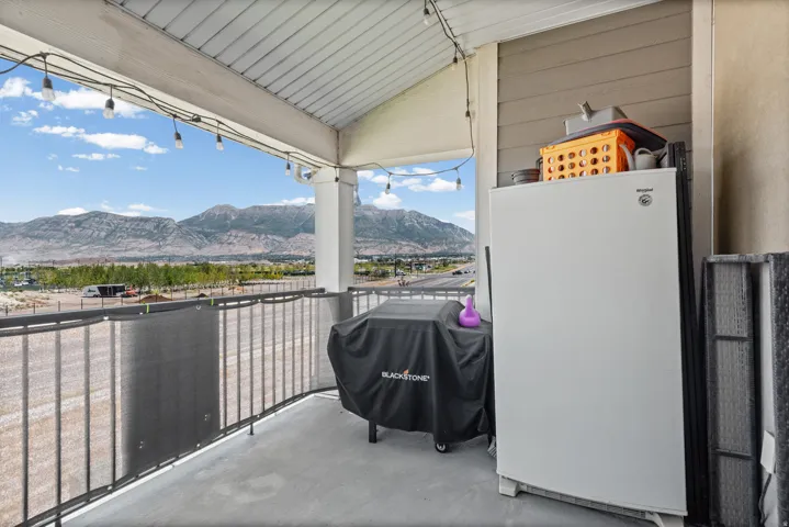 Covered balcony with concrete flooring, white support columns, and wrought iron railing
