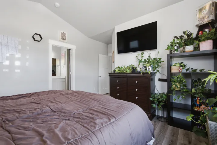 Vaulted ceiling, wood-finish flooring, white trim, and a white interior door
