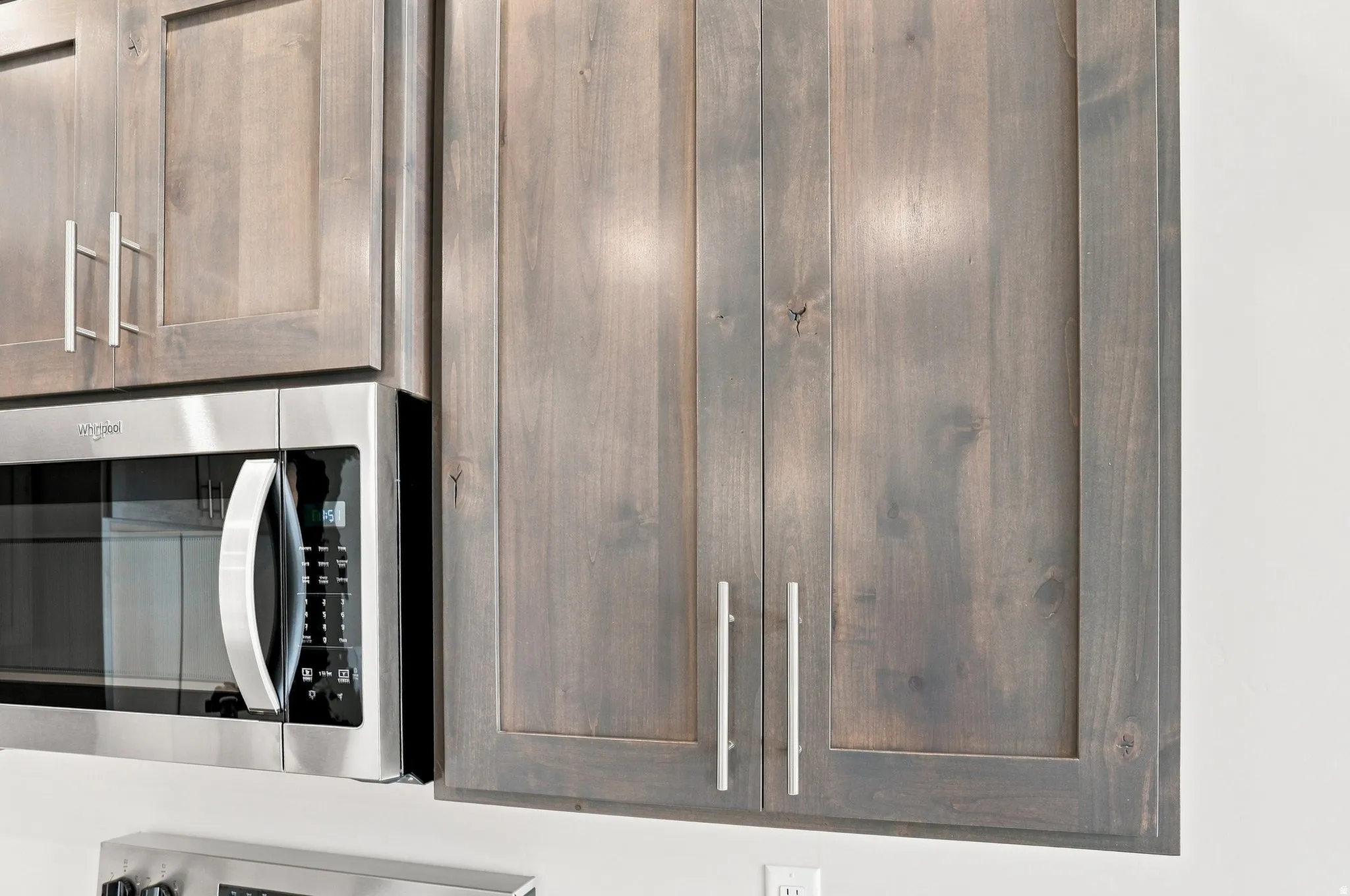 Shaker-style cabinetry, matte silver hardware, and a stainless steel built-in microwave