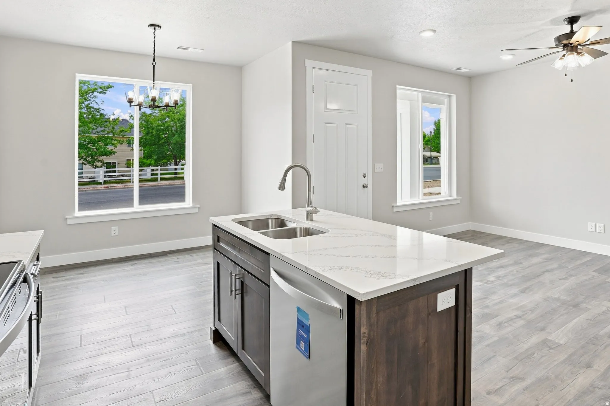 Central island with a dual basin sink and an integrated dishwasher, complemented by light-toned wood-finish flooring