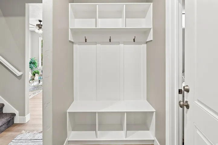 Built-in white storage unit with cubbies, bench, and upper shelving