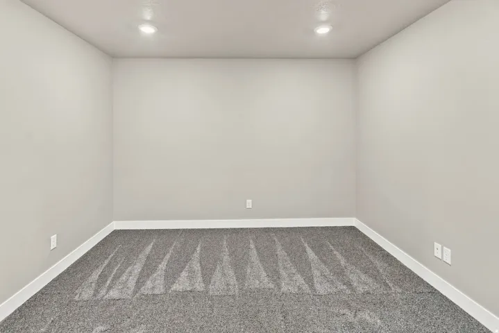 Recessed ceiling lighting, light gray wall paint, white trim, and gray patterned carpeting