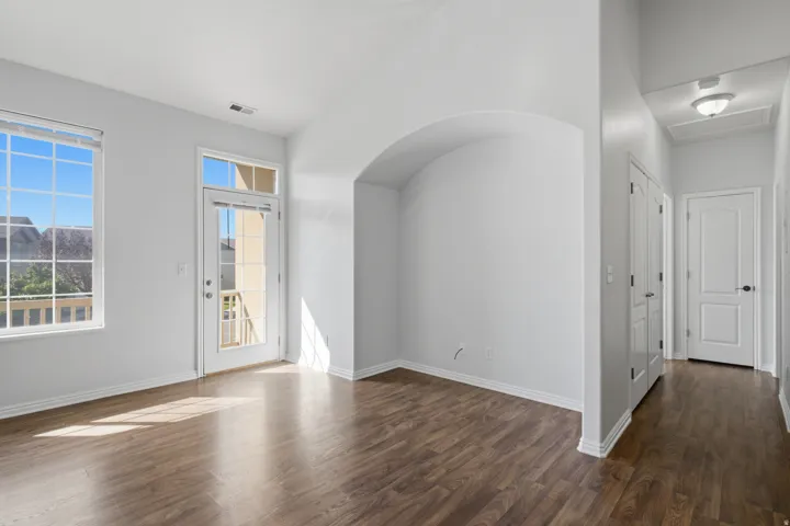 Expansive room featuring wood-finish flooring, a large window, and a glass-paneled door leading to an exterior balcony