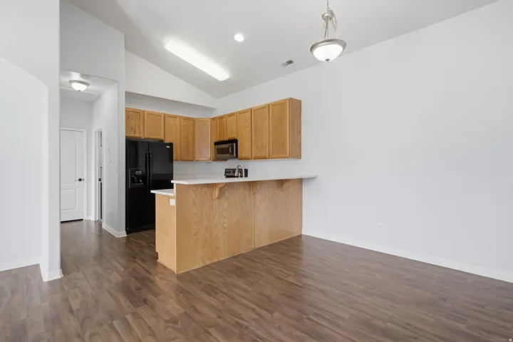 Kitchen featuring wood-finish cabinetry, black appliances, a breakfast bar, and wood-finish flooring