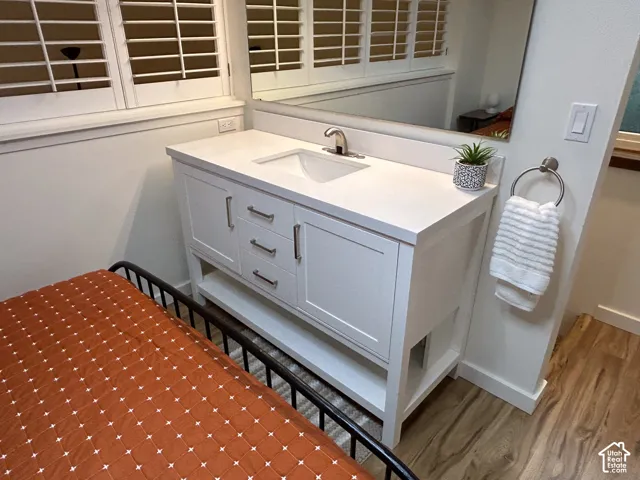 White vanity with an integrated sink and brushed nickel hardware, set on wood-finish flooring
