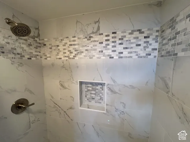 Shower with large format tile, mosaic accent band, built-in niche, and brushed nickel fixtures