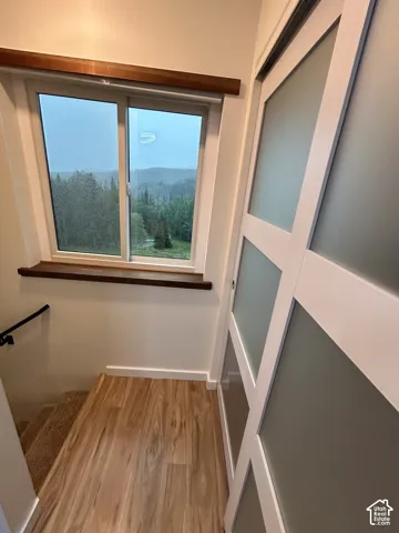 Wood-finish flooring, sliding door with frosted glass panels, wood window trim, and a black handrail