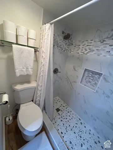 Shower with mosaic tile accents, recessed shower niche, and a pebble-style shower floor