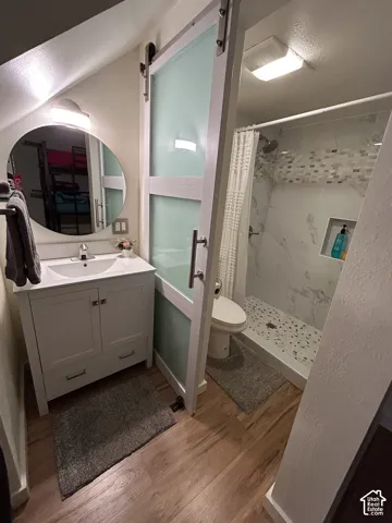 Wood-finish flooring with a white vanity and circular mirror