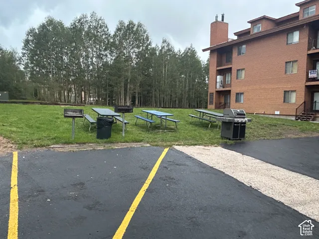 Outdoor communal area with paved parking, a grassy expanse, and mature trees