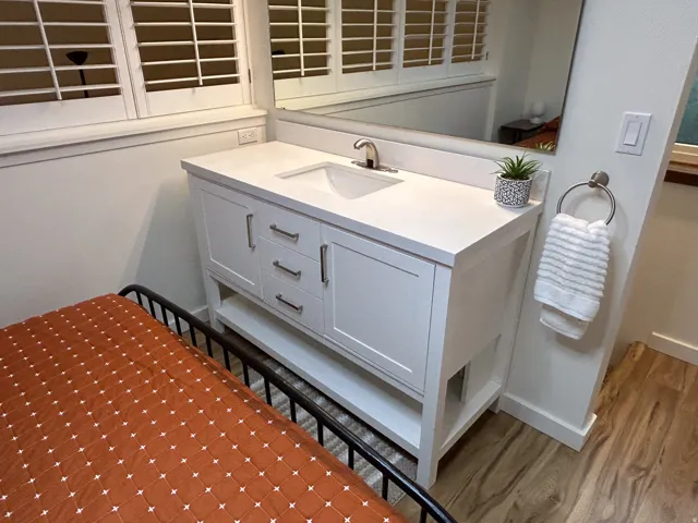 White vanity with an integrated sink and brushed nickel hardware, set on wood-finish flooring