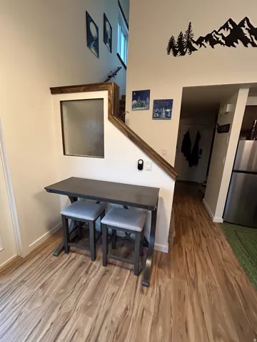 Hardwood-style flooring throughout, custom wood-wrapped half wall with frosted window, and a built-in stainless steel refrigerator