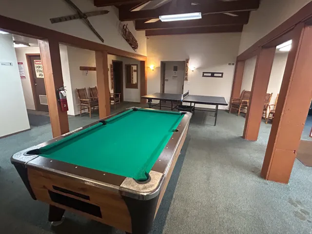 Recreational room featuring a pool table, two ping pong tables, and exposed wood beams