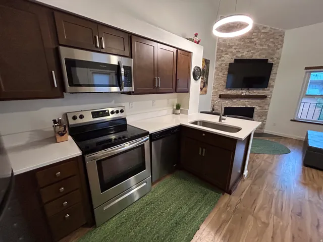 Kitchen featuring dark wood cabinetry, stainless steel appliances, and white countertops
