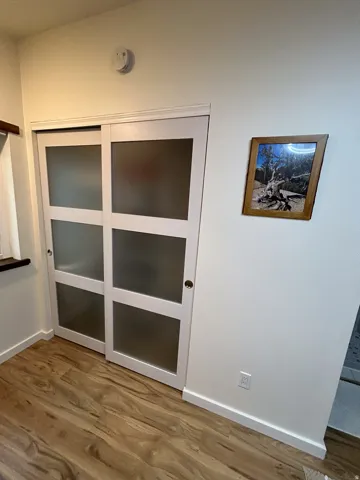 Sliding closet doors with frosted glass panels, wood-finish flooring, and white baseboards