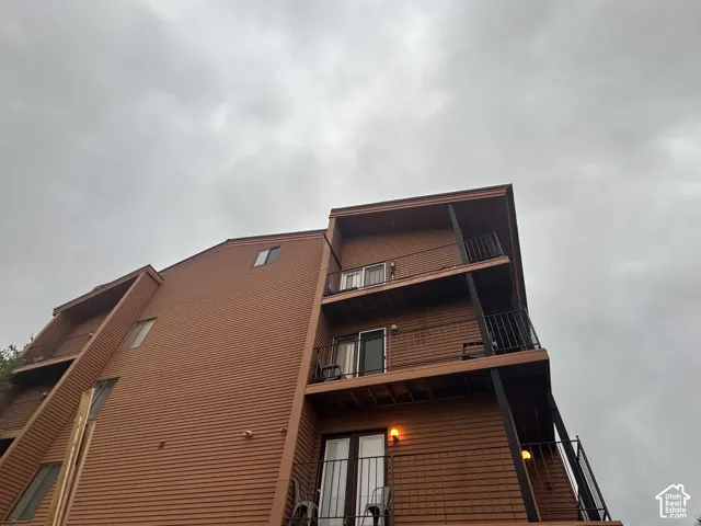 Multi-level exterior with horizontal wood-finish siding, multiple balconies with black metal railings, and integrated wall sconces