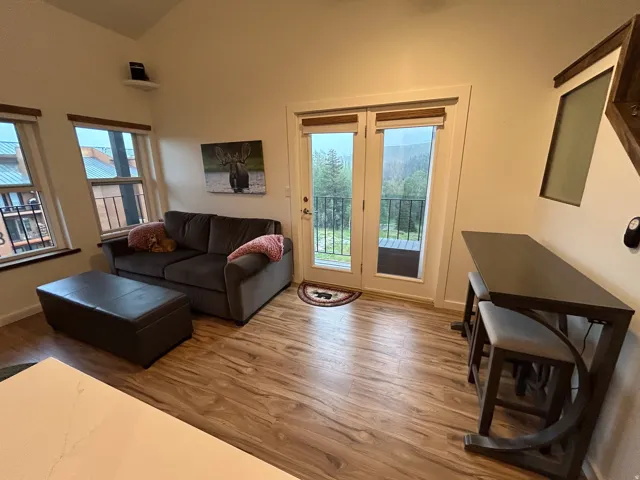 Vaulted ceiling, wood-finish flooring, white walls, and a French door with a balcony
