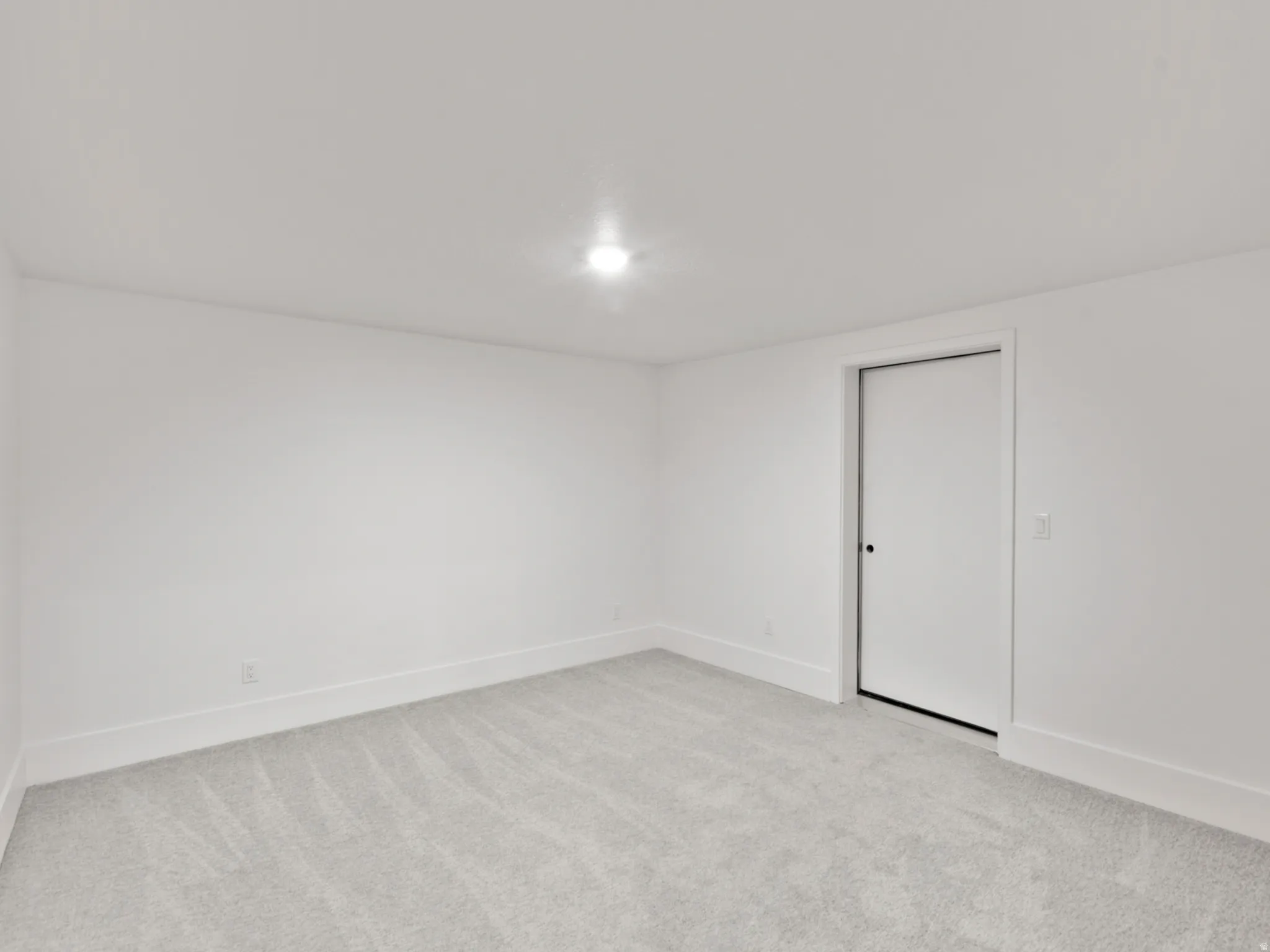 Recessed ceiling light, wall-to-wall carpeting, and white trim