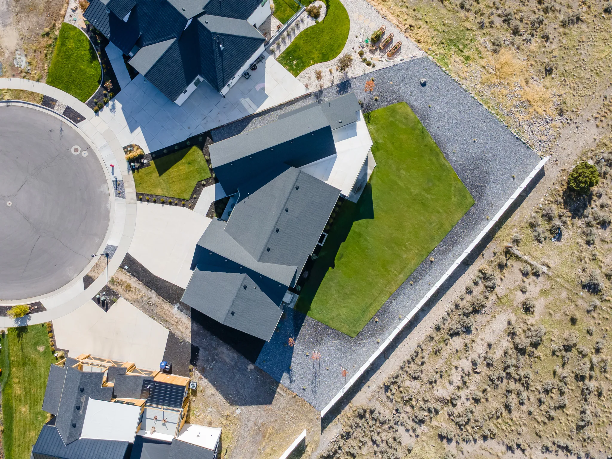 Contemporary property with dark shingle roofing, a manicured lawn, and expansive gravel landscaping