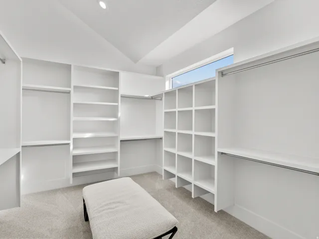 Custom closet system with white shelving, multiple hanging rods, and integrated cubbies