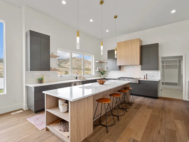 Spacious kitchen featuring an extended island with a light wood-finish base, dark gray cabinetry, white countertops, and a white subway tile backsplash