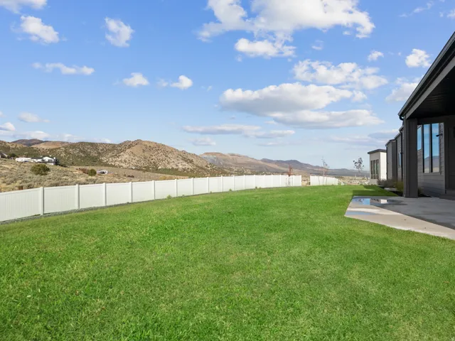 Expansive green lawn with a white privacy fence