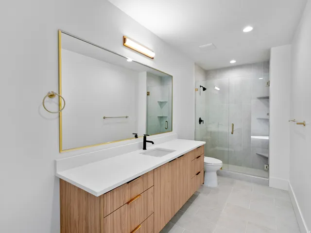 Quartz countertop vanity with wood-finish cabinetry and gold-tone hardware