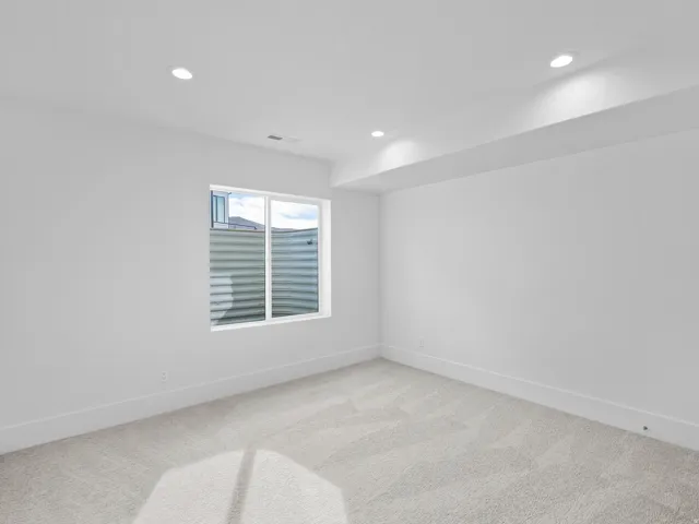 Recessed lighting, light-toned walls, and carpeted flooring