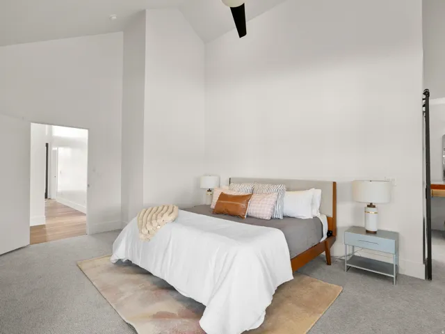 Vaulted ceiling with a ceiling fan, light gray carpeting, and white walls