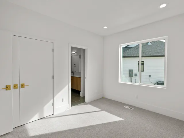 Light gray carpeting, white walls, recessed ceiling lighting, and a white-framed window