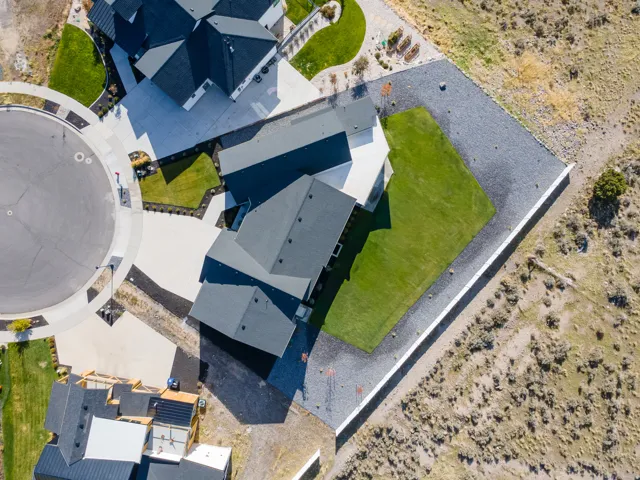 Contemporary property with dark shingle roofing, a manicured lawn, and expansive gravel landscaping