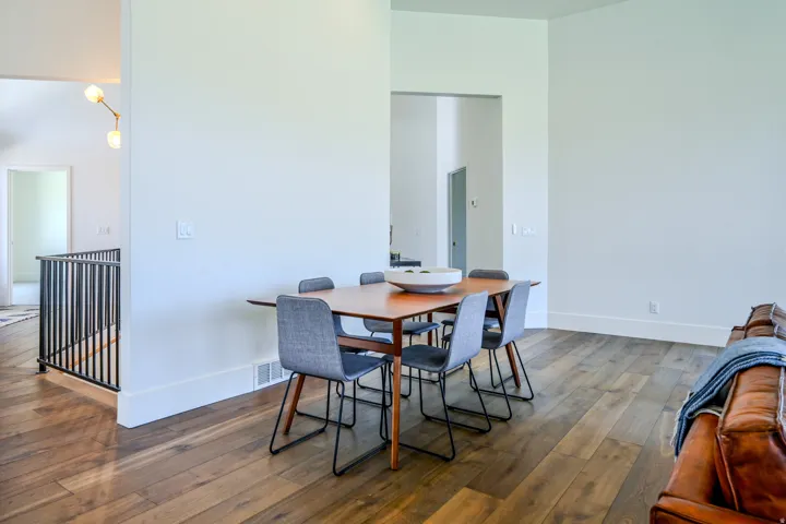Wood-finish flooring throughout, a black metal staircase railing, and a modern ceiling light fixture