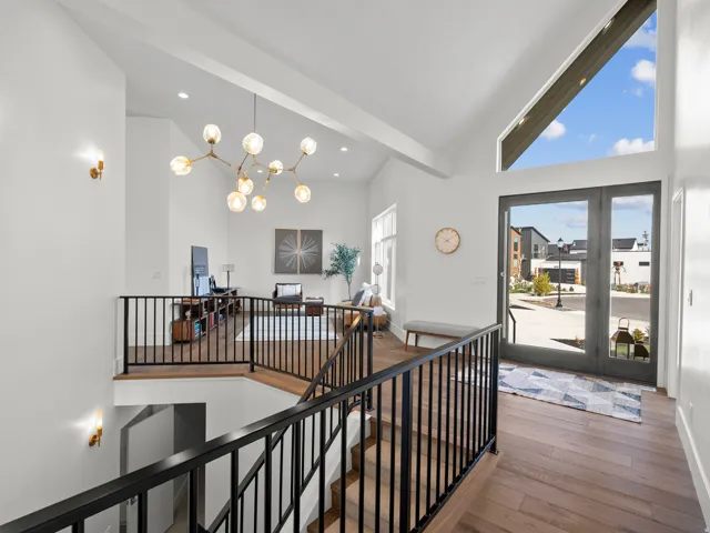 Two-story entry with wood-finish flooring, vaulted ceilings, and a modern chandelier