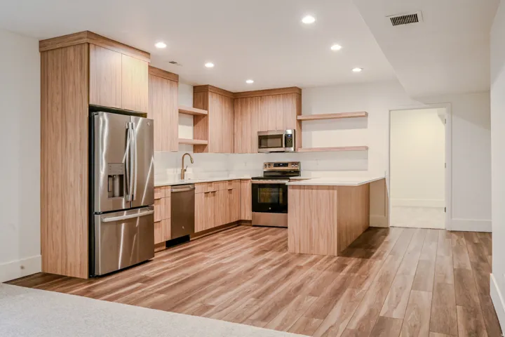 Wood-finish flooring, recessed lighting, stainless steel appliances, light wood cabinetry, and white countertops
