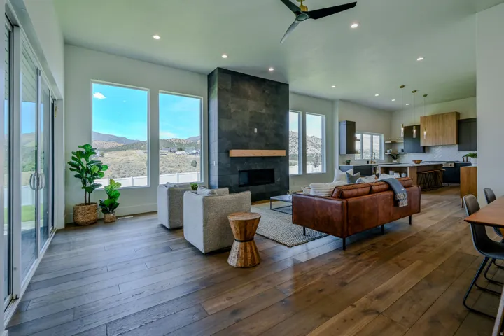 Spacious interior with wood-finish flooring, a contemporary fireplace with a stone surround, recessed lighting, and a modern ceiling fan