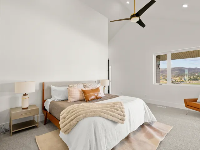 Vaulted ceiling with a ceiling fan, large window, and carpeted flooring