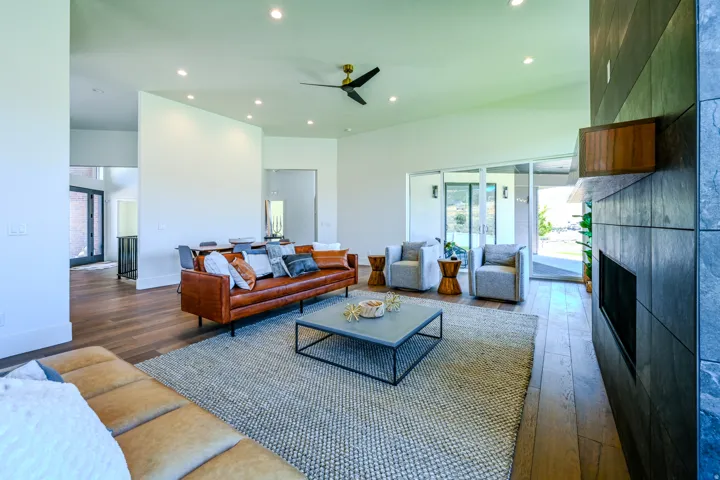 Spacious living area featuring wood-finish flooring, recessed lighting, a ceiling fan, and an integrated fireplace with a stone-tiled surround