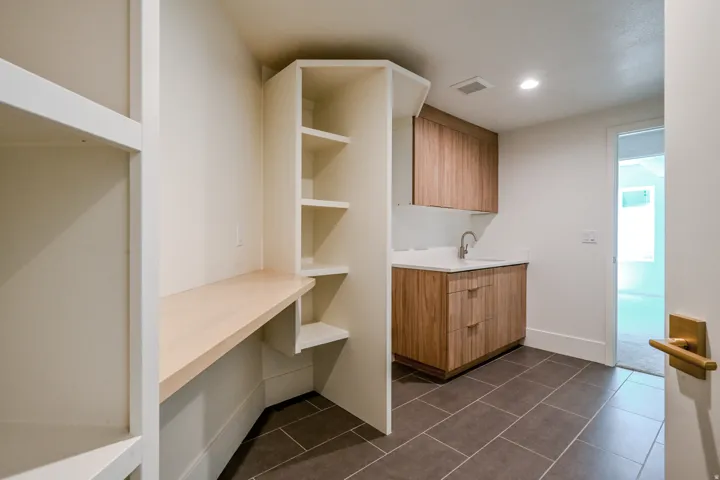 Built-in shelving, integrated desk, wood-finish cabinetry, white countertop, and tiled flooring